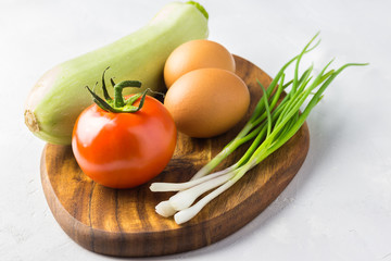 Fresh vegetables and eggs on wooden board.  Ingredients for salad, frittata, omelet or muffins.