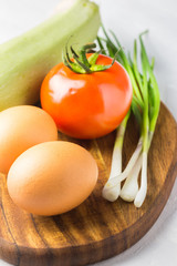 Raw vegetables and eggs on wooden board. Ingredients for salad, frittata, omelet or muffins.