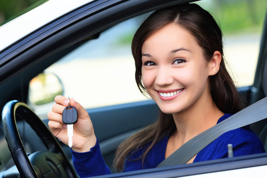 Beautiful young smiling happy girl shows the car key in her hand