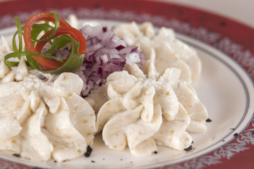 Fish roe salad, whit toasted bread, onion, green leafs, lemon, radish and olives, placed on a white plate, brown background