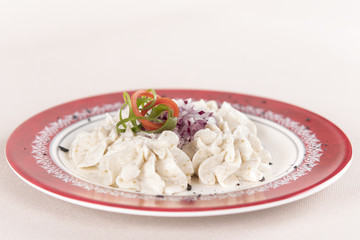 Fish roe salad, whit toasted bread, onion, green leafs, lemon, radish and olives, placed on a white plate, brown background
