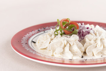 Fish roe salad, whit toasted bread, onion, green leafs, lemon, radish and olives, placed on a white plate, brown background
