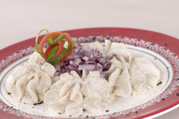 Fish roe salad, whit toasted bread, onion, green leafs, lemon, radish and olives, placed on a white plate, brown background
