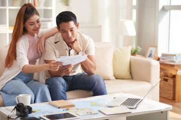 Portrait of happy Asian couple discussing travelling plans at home