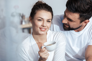 Portrait of young woman having coffee with boyfriend in bed