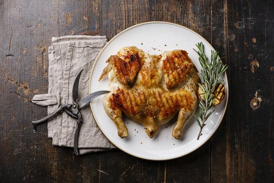 Grilled fried roast Chicken Tabaka on plate on wooden background