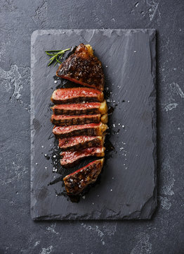 Sliced medium rare grilled Striploin steak on slate board