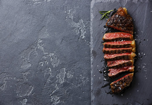 Sliced medium rare grilled Striploin steak on slate board copy space