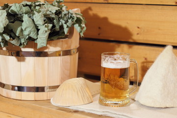 A mug of light beer and bath accessories are in the interior of the Russian bath.