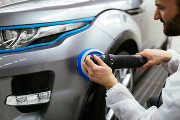 Car detailing - Hands with orbital polisher in auto repair shop. Selective focus. 