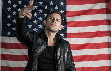 Tough guy in a leather jacket against the background of the American flag