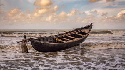 Fisherman tries to tow his boat to shore at Tajpur beach in West Bengal, India.