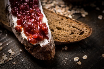 Fruity Jam on Traditional Whole Grain Rye Bread on Dark Wooden Table Background