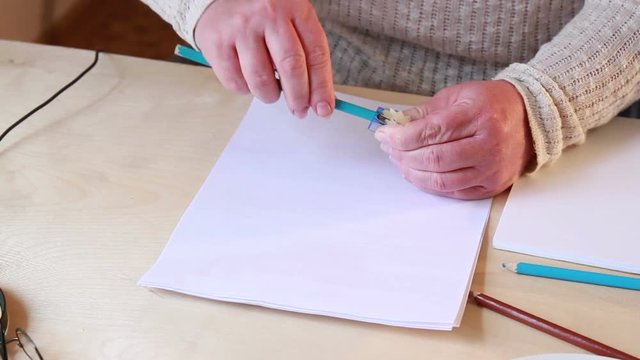 Female hands sharpen blue pencil