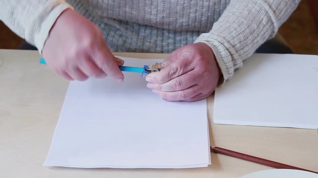 Boy paints the sky and female hands sharpen blue pencil