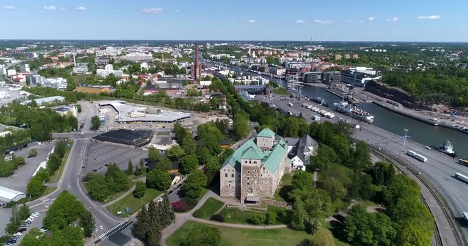 Turku castle, Cinema 4k aerial backward tilt view of turun linna, revealing turku city and aurajoki, on a sunny summer day, in Abo, Finland