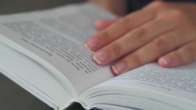 Book pages. The book, reading. A woman's hand holds the pages of the book. A woman's hand turns over the pages of the book. Concept: reading, books, bookmark.