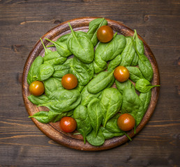 Detox and diet food concept Fresh spinach on a cutting board with cherry tomatoes on a rustic wooden background