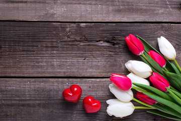 Two red decorative hearts  and bright  spring  tulips flowers