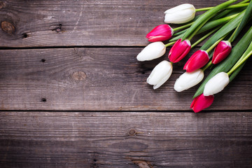 Fototapeta na wymiar Bunch of bright pink and white tulips flowers on aged wooden background