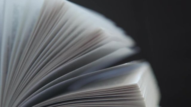 Opened book on a dark background (isolated): leafing through books. Concept reading, books, flipping books. Book pages on a dark background.