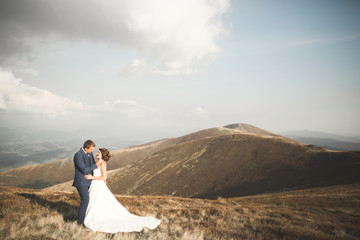 Beautifull wedding couple kissing and embracing near mountain with perfect view