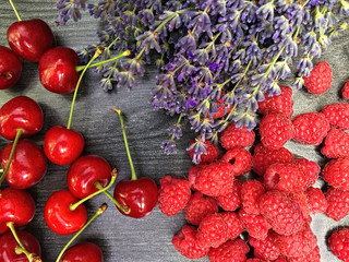 Mix of fresh berries and lavender flowers on black wooden background summer organic berry, cherries and raspberry