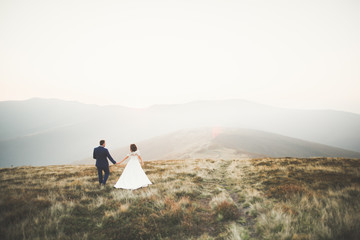 Fototapeta premium Beautiful wedding couple posing on top of a mountain at sunset