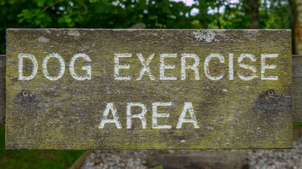 A wooden dog exercise area sign with white letters