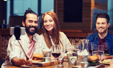 friends taking selfie by smartphone at restaurant