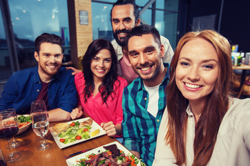 friends taking selfie by smartphone at restaurant