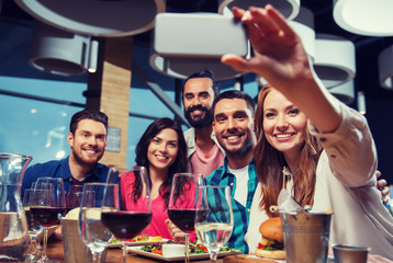 friends taking selfie by smartphone at restaurant