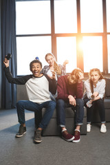 happy multicultural teenagers playing video games with joysticks at home, teenagers having fun concept