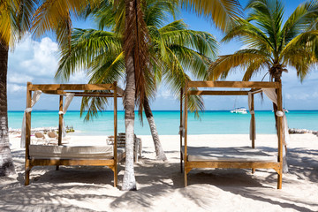 Luxuriöse Sonnenbetten am karibischen Strand mit Palmen in Mexiko