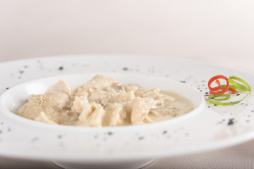 Tripe soup, served with garlic sauce – “mujdei” and horseradish sauce, decorated with green and red leafs, placed on white plate, light background, isolated