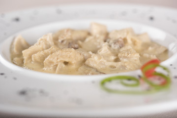Tripe soup, served with garlic sauce – “mujdei” and horseradish sauce, decorated with green and red leafs, placed on white plate, light background, isolated