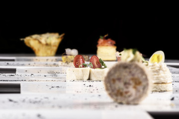 Different types of canapes, placed on individual plates, finger food, dark background