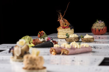Different types of canapes, placed on individual plates, finger food, dark background