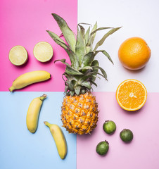 concept of summer fruit set against a bright background mini pineapple, mango, mini bananas, carambola, lime, quince, top view
