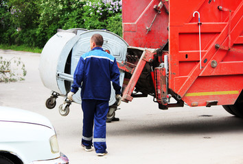 worker loads rubbish bin at a recycling machine.