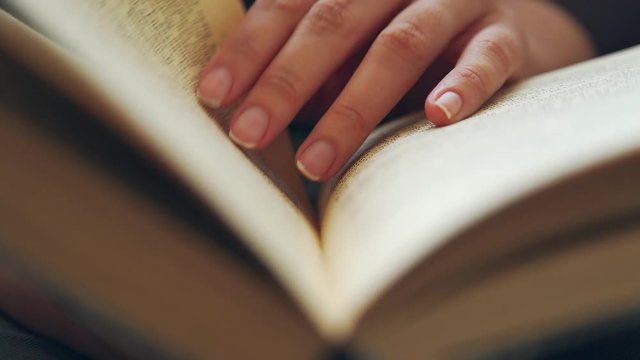 Hand and book: reading a book and holding your fingers along the lines. A woman's hand holds a book and moves her fingers along the page while reading. The reader of the book holds