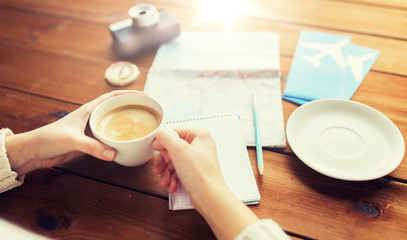close up of hands with coffee cup and travel stuff