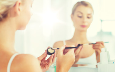 Obraz na płótnie Canvas woman with makeup brush and eyeshade at bathroom