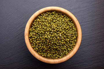 mung bean in a wooden cup on a black stone board background, space for text, beans