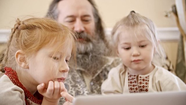 Closeup of man with long beard watching something on laptop with little son and daughter