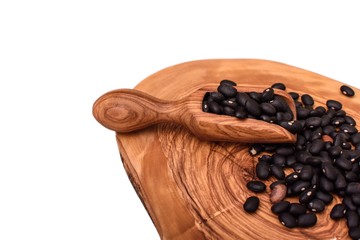 Black beans on an olive board isolated on a white background
