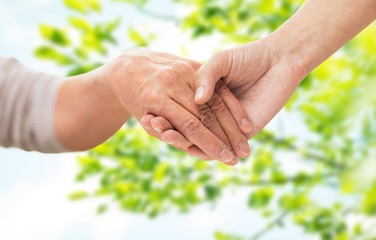 close up of senior and young woman holding hands