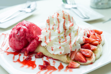 ice cream strawberry crepe dessert on white dish wood table in cafe coffee shop sweet food