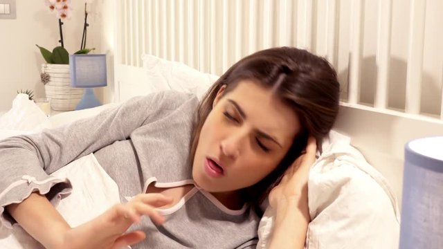 Woman coughing in bed feeling sick