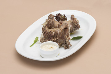Turkey necks, served with horseradish puree, placed on white plate, light background, isolated
